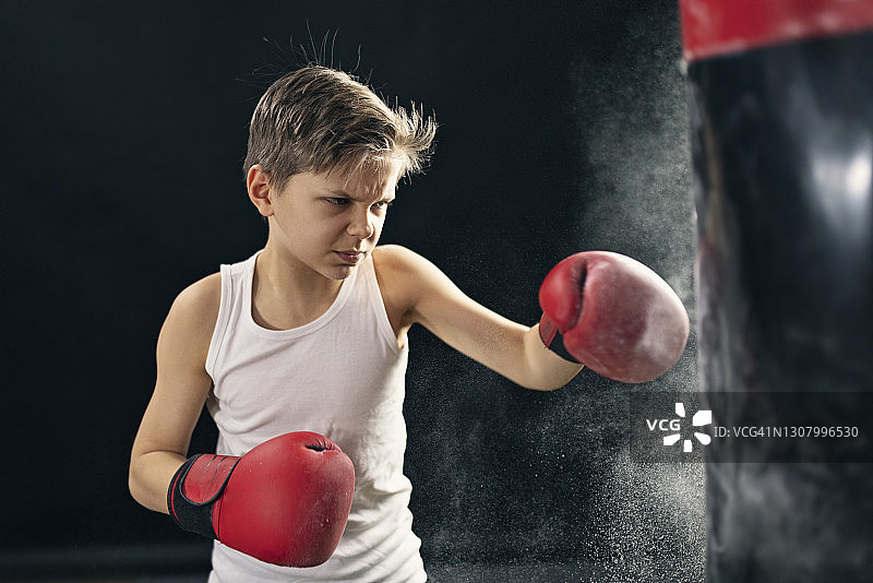 小男孩训练拳击打沙袋图片素材