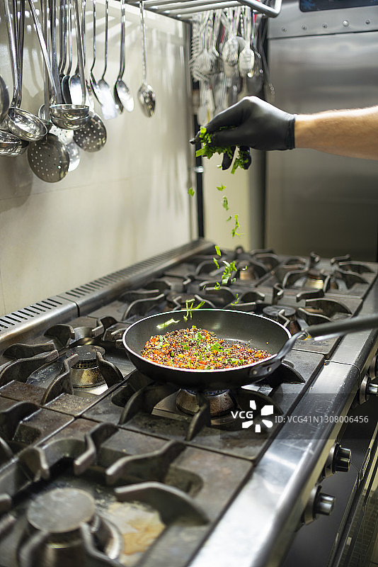 厨师在餐厅厨房的炉子上用平底锅烹饪图片素材