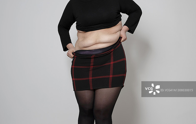 灰色背景下，年轻肥胖女人的腰部特写图片素材
