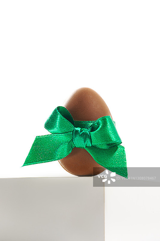 白色底座背景上的绿色丝带巧克力复活节彩蛋，已隔离图片素材
