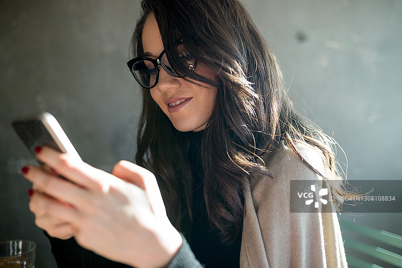 坐在咖啡馆使用智能手机的商务女人图片素材