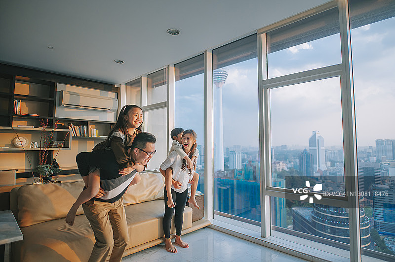 华人家庭在吉隆坡客厅玩背 piggyback 游戏图片素材