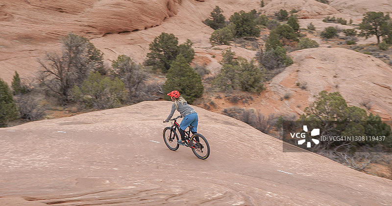 年轻女人在沙漠环境中骑山地自行车图片素材