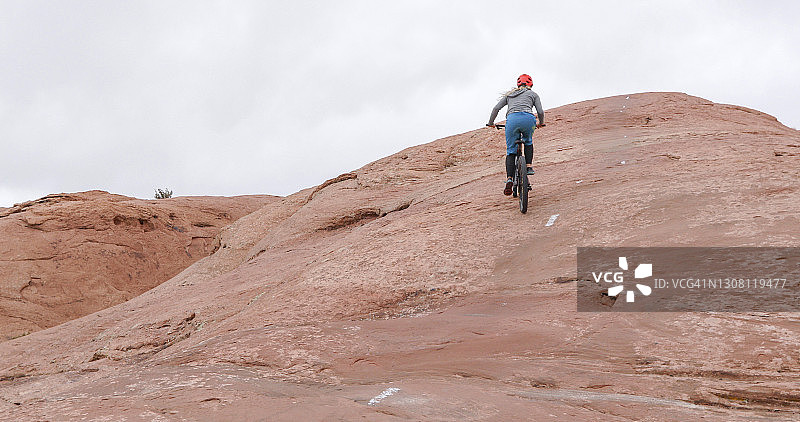 年轻女人在沙漠环境中骑山地自行车图片素材