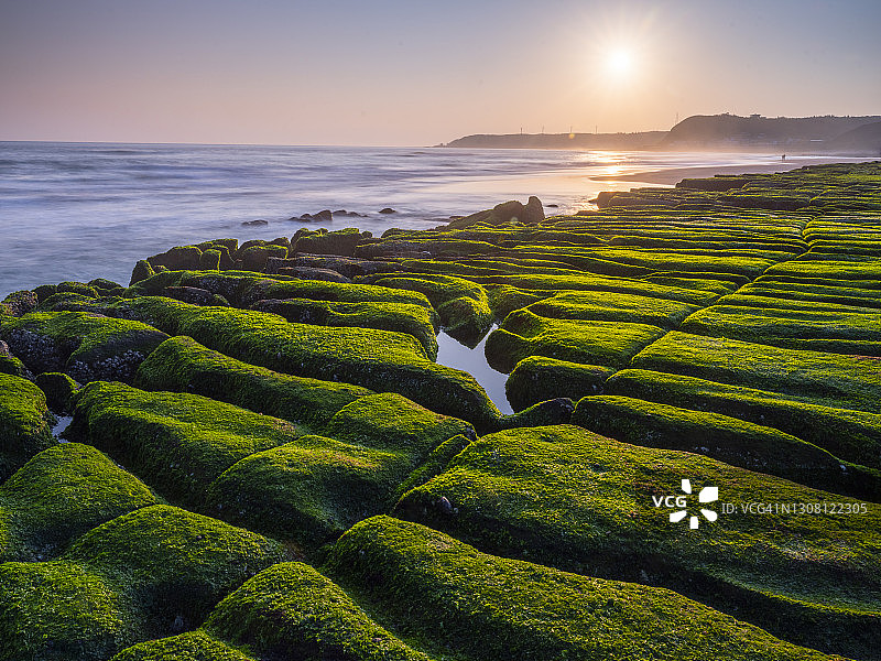 中国台湾新北市石门区老梅绿石槽。在东北季风的影响下，海浪拍打着礁石表面，海莴苣和“绿发”等绿色藻类缓慢生长，形成了老梅绿石槽的季节性景观图片素材