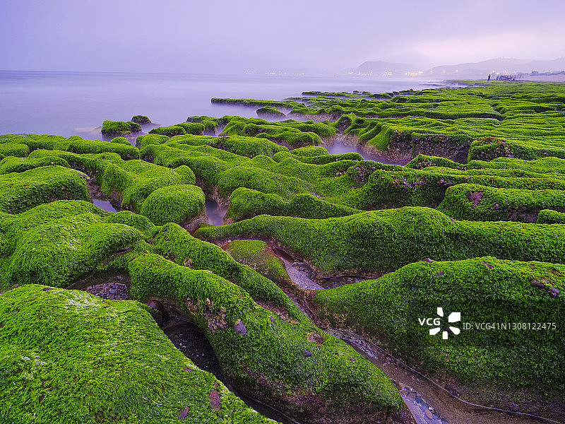 中国台湾新北市石门区老梅绿石槽。在东北季风的影响下，海浪拍打着礁石表面，海莴苣和“绿发”等绿色藻类缓慢生长，形成了老梅绿石槽的季节性景观图片素材