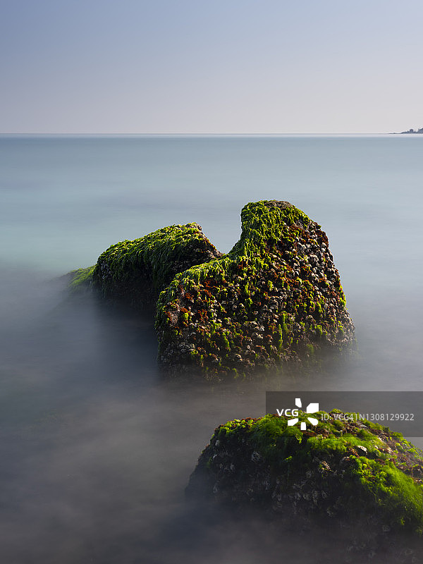 中国台湾新北市石门区老梅绿石槽。在东北季风的影响下，海浪拍打着礁石表面，海莴苣和“绿发”等绿色藻类缓慢生长，形成了老梅绿石槽的季节性景观图片素材