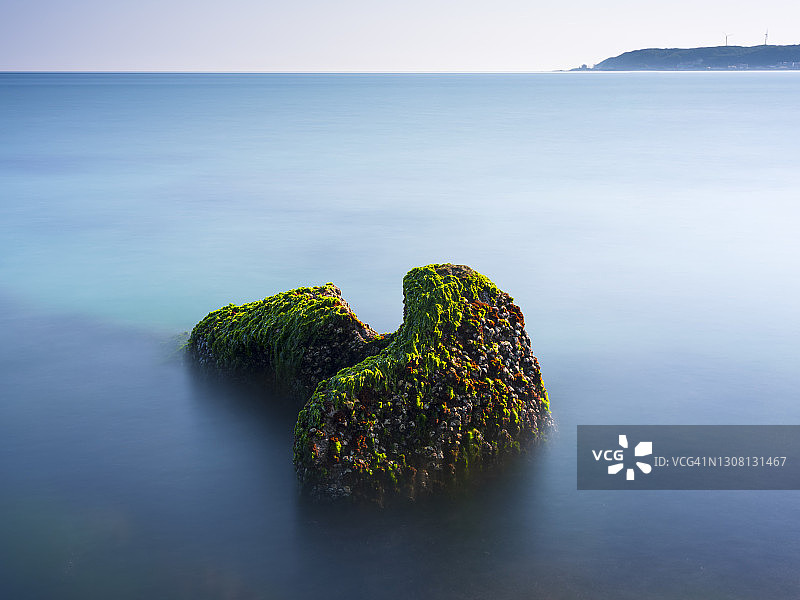 中国台湾新北市石门区老梅绿石槽。在东北季风的影响下，海浪拍打着礁石表面，海莴苣和“绿发”等绿色藻类缓慢生长，形成了老梅绿石槽的季节性景观图片素材