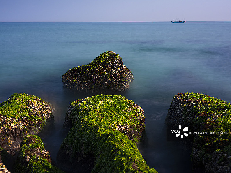中国台湾新北市石门区老梅绿石槽。在东北季风的影响下，海浪拍打着礁石表面，海莴苣和“绿发”等绿色藻类缓慢生长，形成了老梅绿石槽的季节性景观图片素材