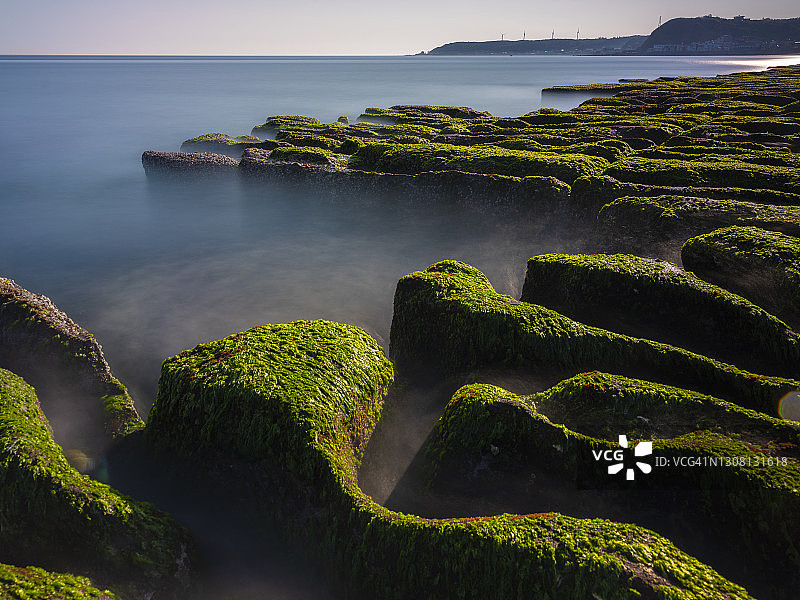 中国台湾新北市石门区老梅绿石槽。在东北季风的影响下，海浪拍打着礁石表面，海莴苣和“绿发”等绿色藻类缓慢生长，形成了老梅绿石槽的季节性景观图片素材