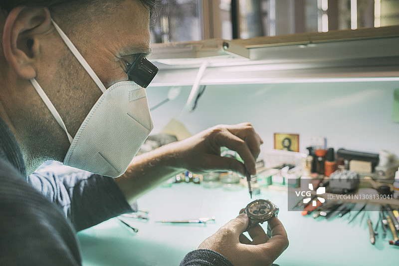 戴着放大镜修理手表的男人图片素材