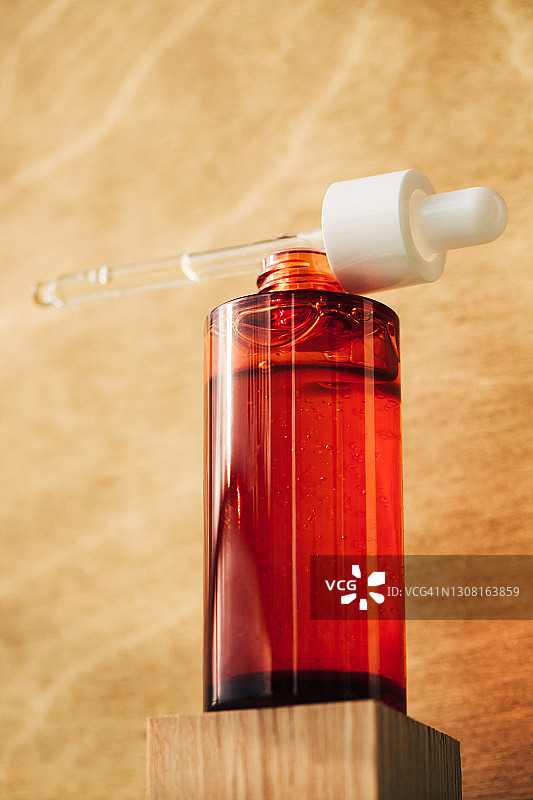 木质背景上的红色玻璃滴管瓶精油润肤露图片素材