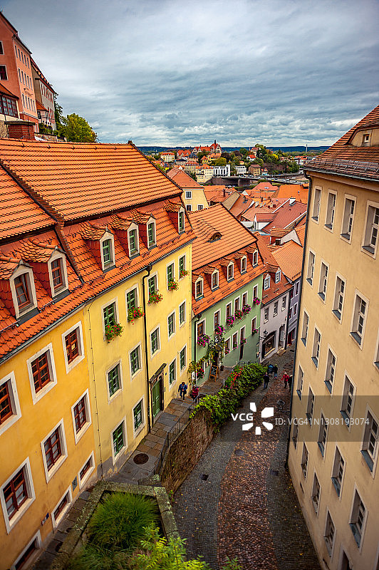在Meissen老城区，人们走在鹅卵石街道上，街道两旁排列着古典传统的德国建筑图片素材