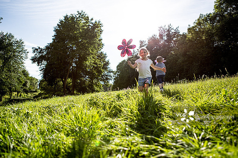儿童在草地上玩风车图片素材