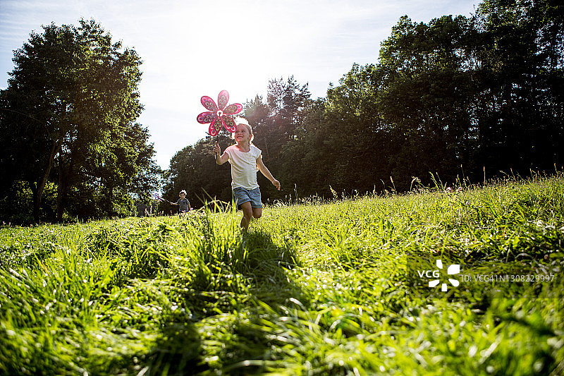 儿童在草地上玩风车图片素材