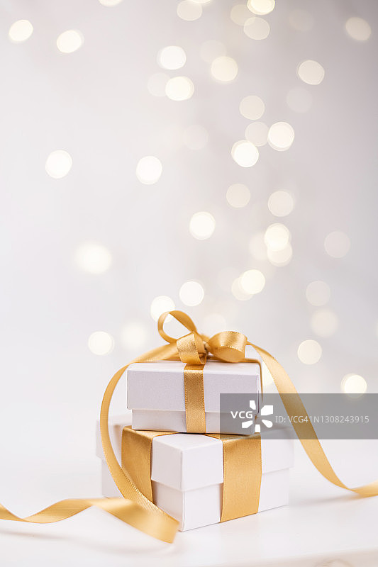 散景背景上的金色丝带白色礼品盒堆图片素材