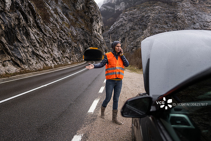 身穿反光背心站在故障车旁打电话的女人图片素材