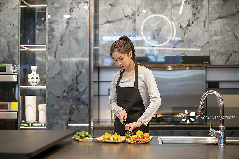 在厨房切菜的亚洲年轻女人图片素材