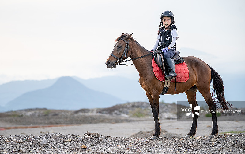 年轻女孩戴着头盔骑马图片素材