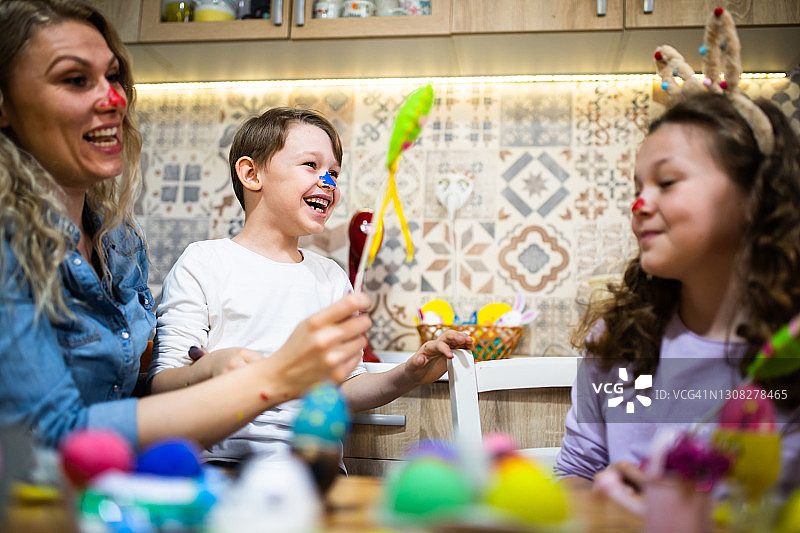 一位年轻的母亲和她的两个孩子一起为复活节彩蛋涂色图片素材