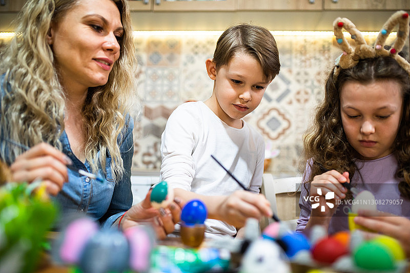 可爱的男孩和家人一起给复活节彩蛋涂色图片素材
