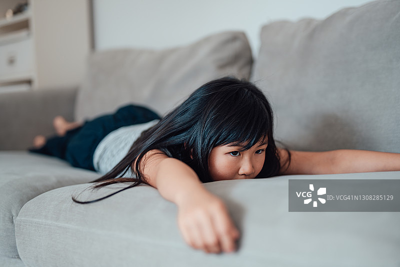 躺在沙发上感到无聊的年轻亚洲女孩图片素材