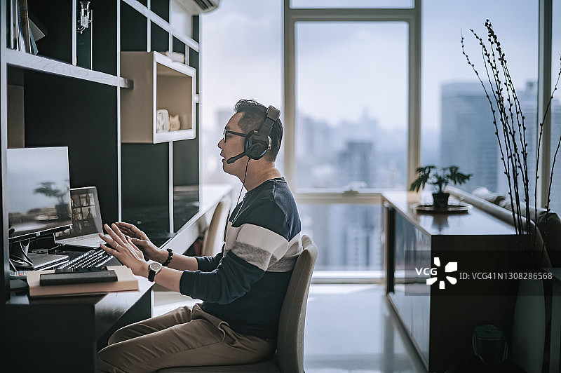在家用耳机进行视频通话的中国籍中年男子图片素材