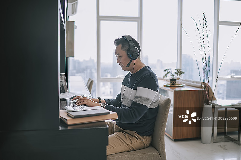 在家用耳机进行视频通话的中国籍中年男子图片素材