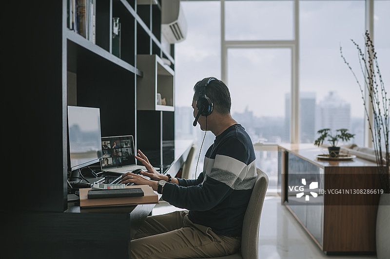 在家用耳机进行视频通话的中国籍中年男子图片素材