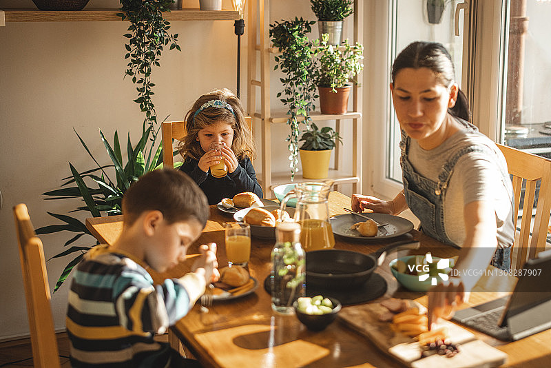两个孩子和母亲在早餐桌旁图片素材