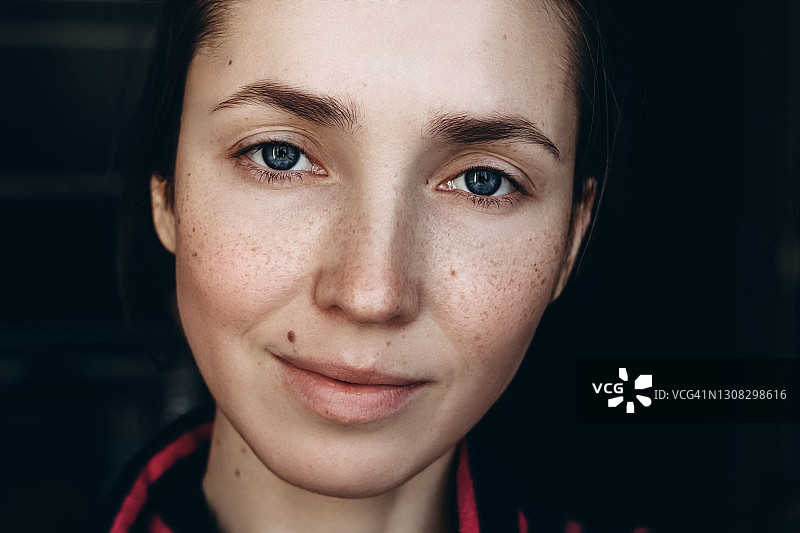 年轻女人的蓝色眼睛、痣和雀斑肖像图片素材