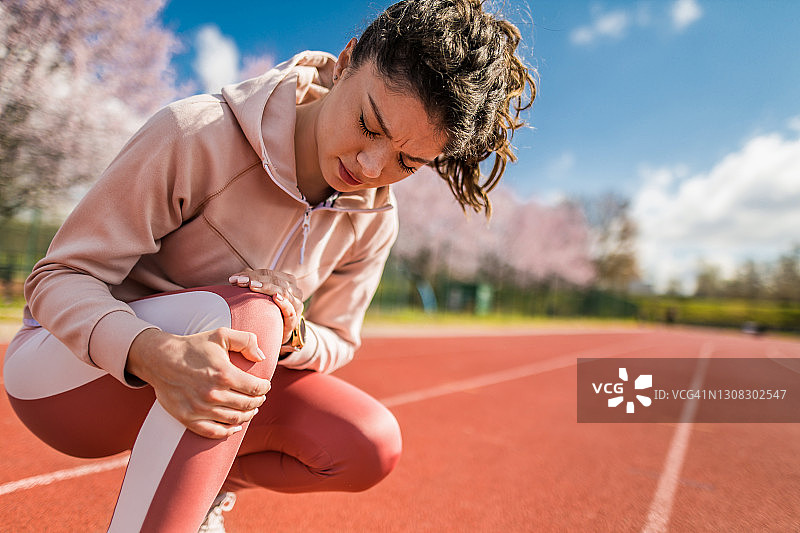 膝盖受伤的年轻运动女性图片素材