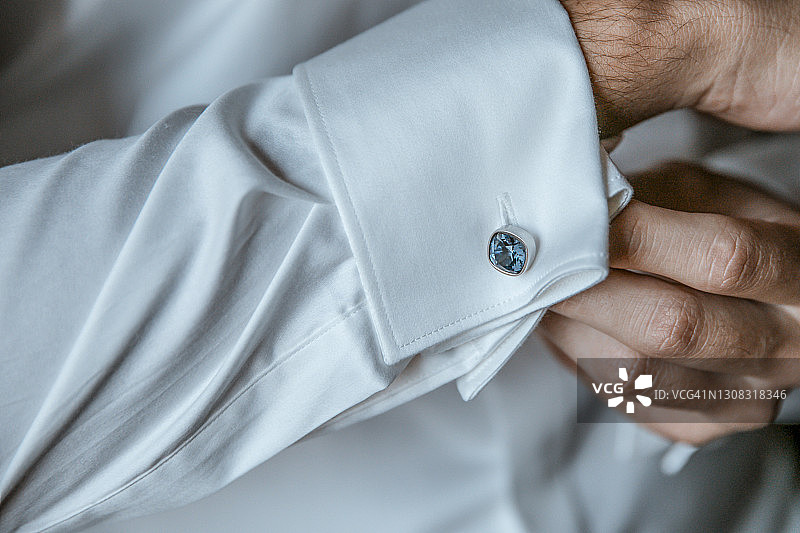 男人将袖扣系在衬衫上的手部特写图片素材