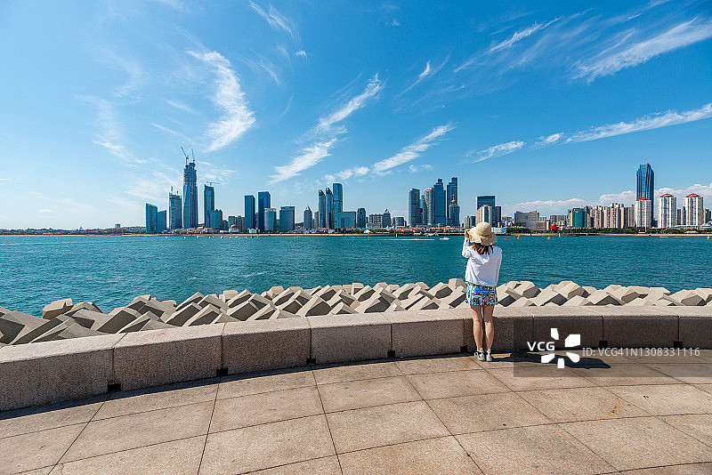 美丽女人欣赏青岛市中心海滨天际线（蓝天，留白）图片素材