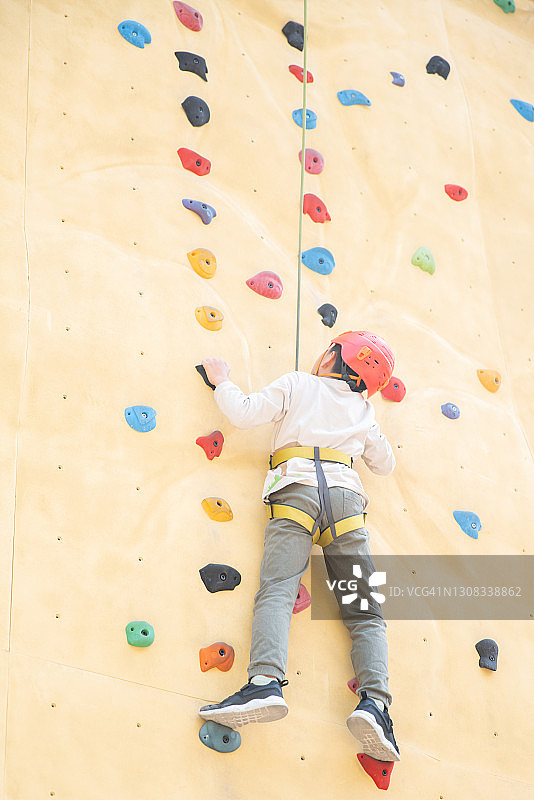 在户外攀岩墙上攀爬的男孩图片素材