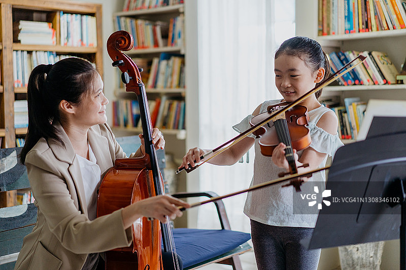 美丽的母亲在家和可爱的女儿一起演奏乐器图片素材