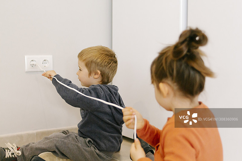 兄弟俩试图拔掉电器插头图片素材