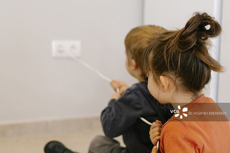 兄弟俩试图拔掉电器插头图片素材