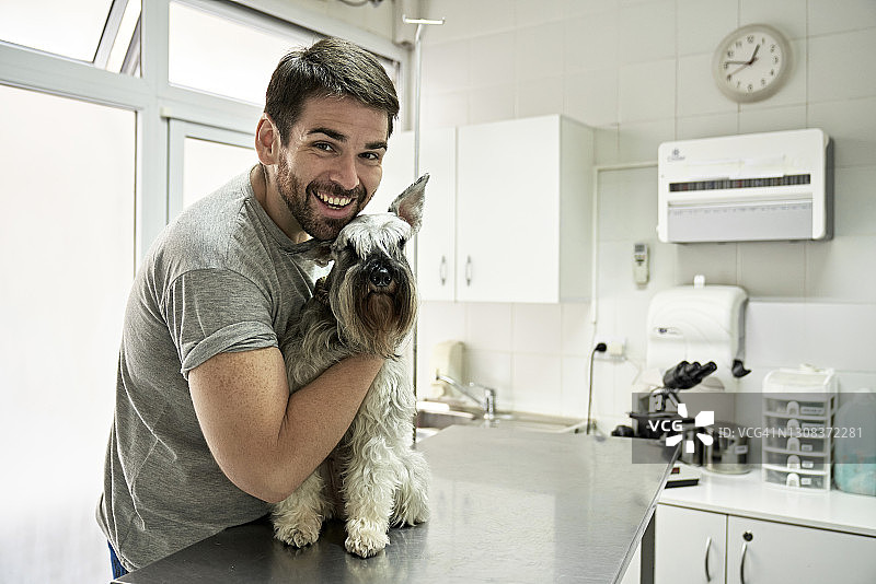 快乐的宠物主人和迷你雪纳瑞犬等待体检图片素材