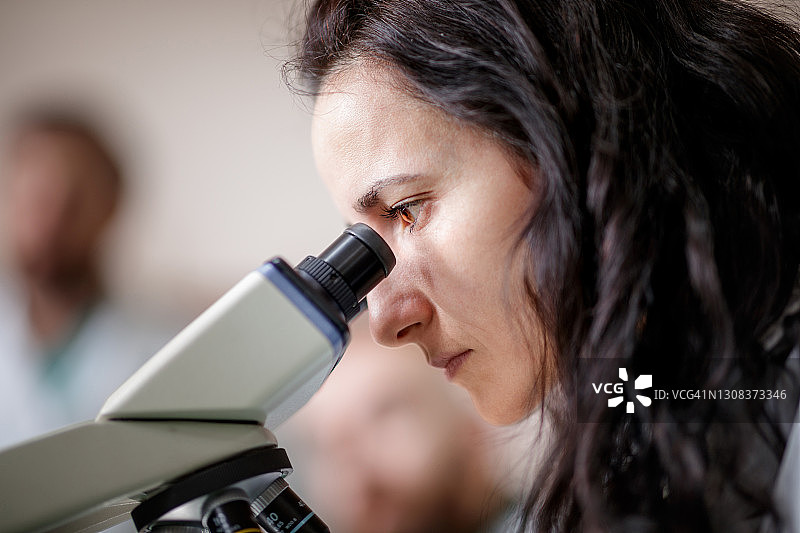 观察显微镜的美丽女子侧面照图片素材