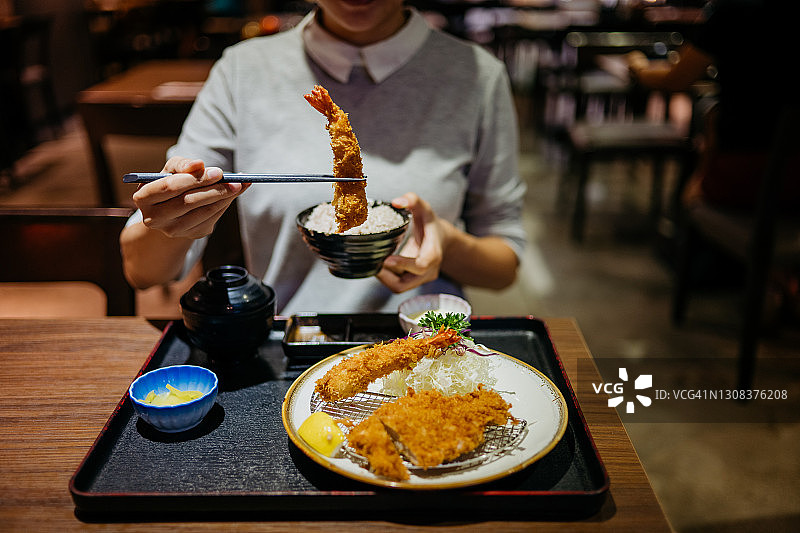年轻女人在餐厅吃日式炸猪排套餐图片素材