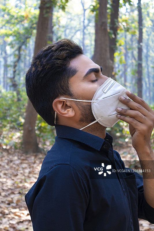 男子在森林里呼吸新鲜空气，试图摘下口罩图片素材