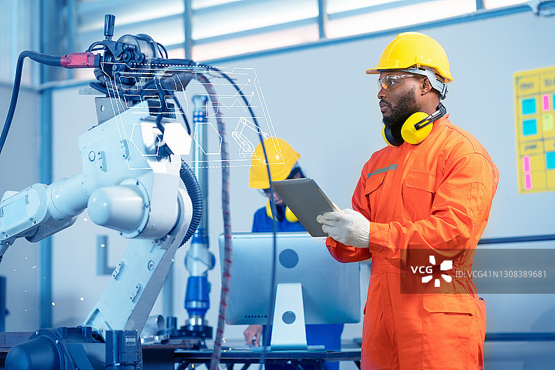 工程师检查机器人的编程。他已经解决了机器人手臂工作和移动金属工业的方案图片素材