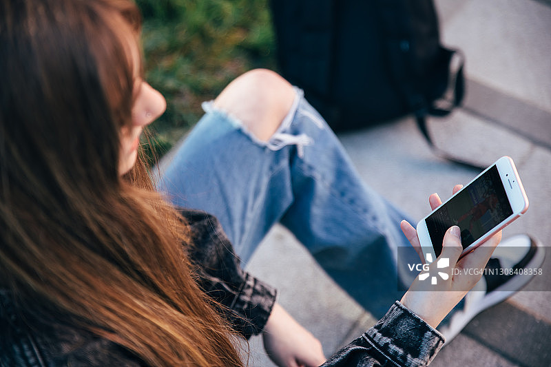 在户外使用智能手机的青少年学生图片素材