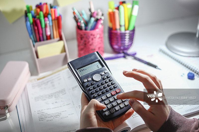 学生使用计算器、彩色铅笔和笔筒学习图片素材