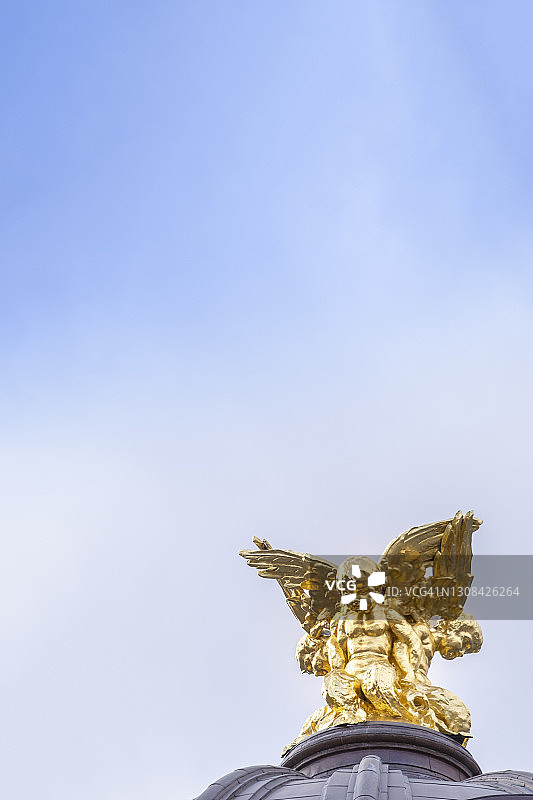 蓝天下建筑屋顶上的金色翅膀天使图片素材