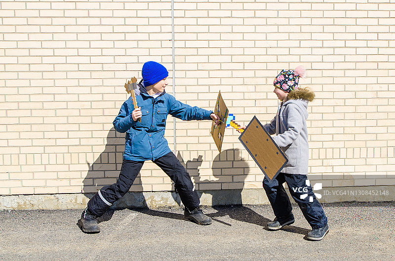 两个孩子用纸板斧头和盾牌打闹图片素材