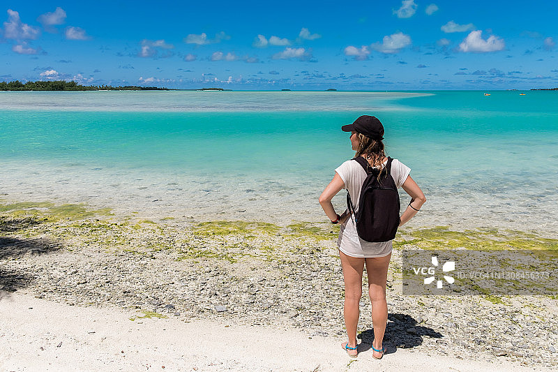 阳光明媚的日子里，女孩眺望艾图塔基泻湖的岛屿图片素材