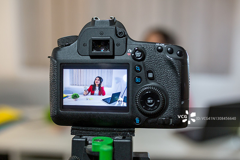 为视频博客录制内容的女性视频博主，专注于数码相机屏幕的年轻女人图片素材