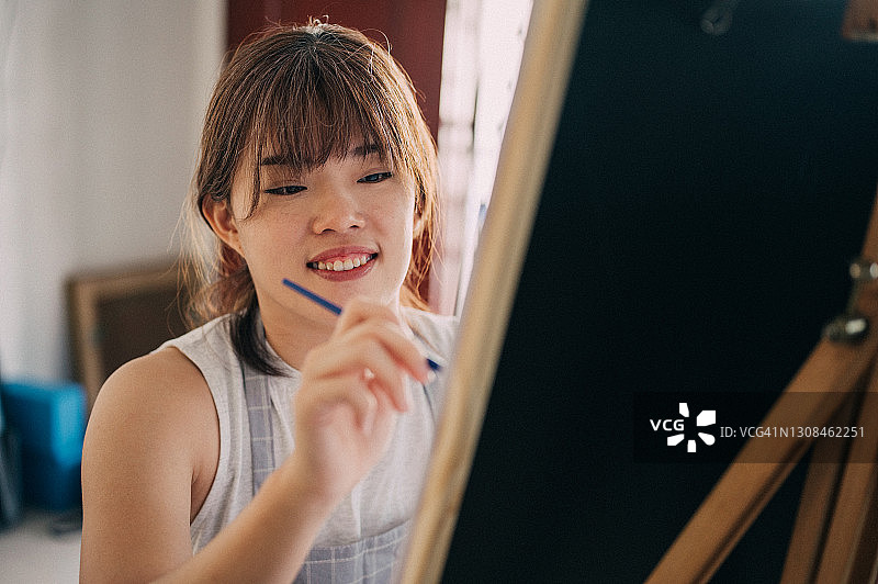 在画架上绘画的快乐女人图片素材